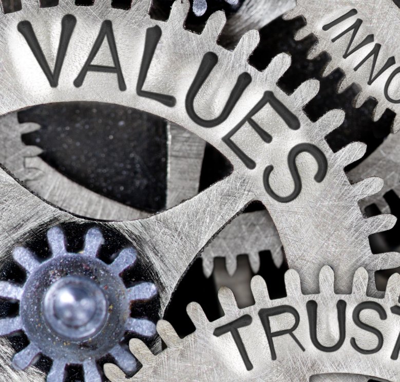 Image of gears intertwined, engraved with words 'values' and 'trust' for reference to JTE Claims Consultants Ltd company values.